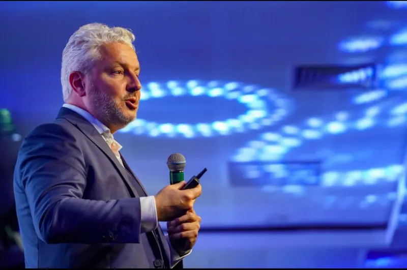 Ricardo Wagner speaking into a microphone, photographed in profile.