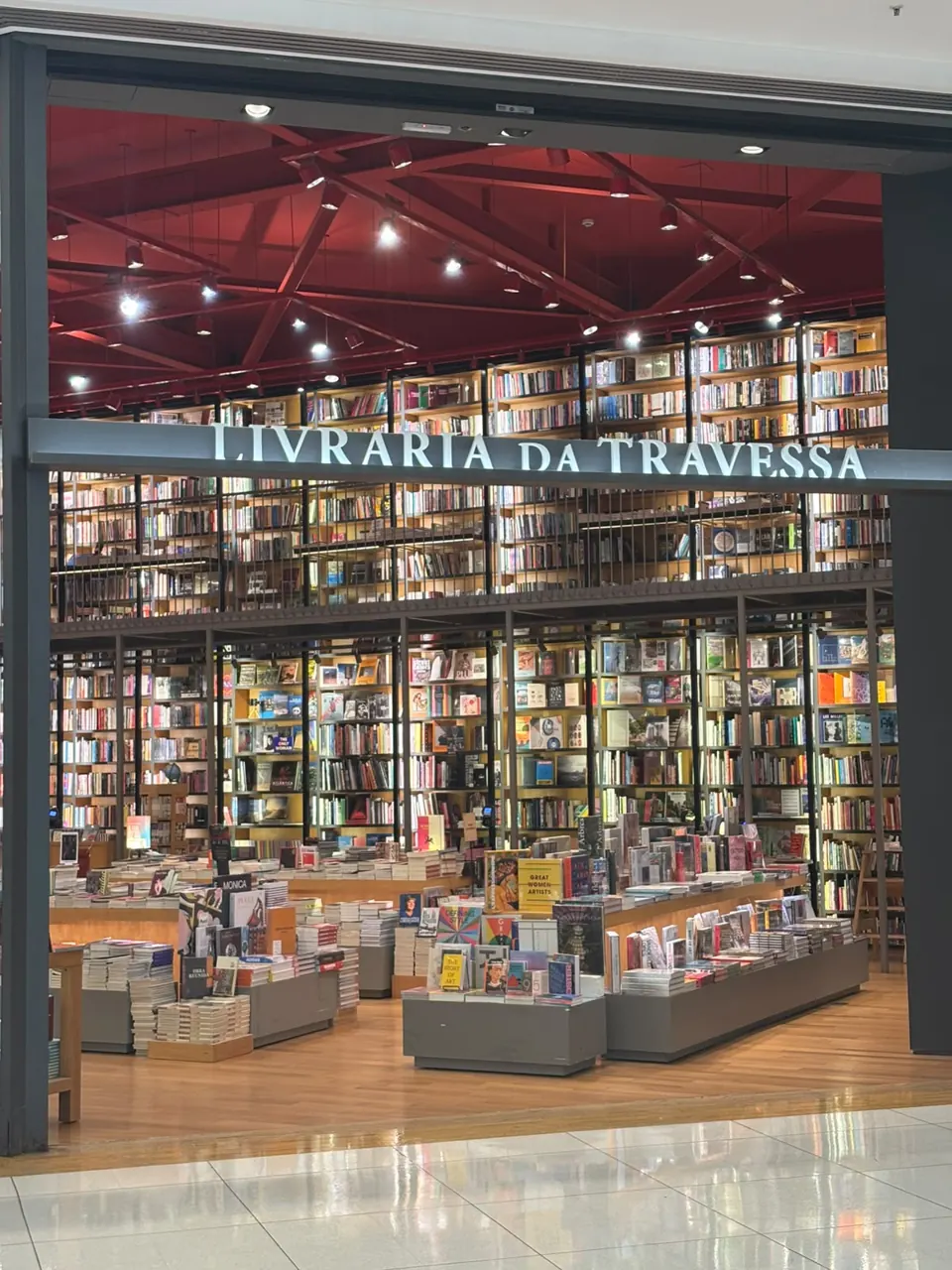 Fachada da Livraria da Travessa no Shopping Iguatemi, com o letreiro sobre a entrada e as estantes de livros.